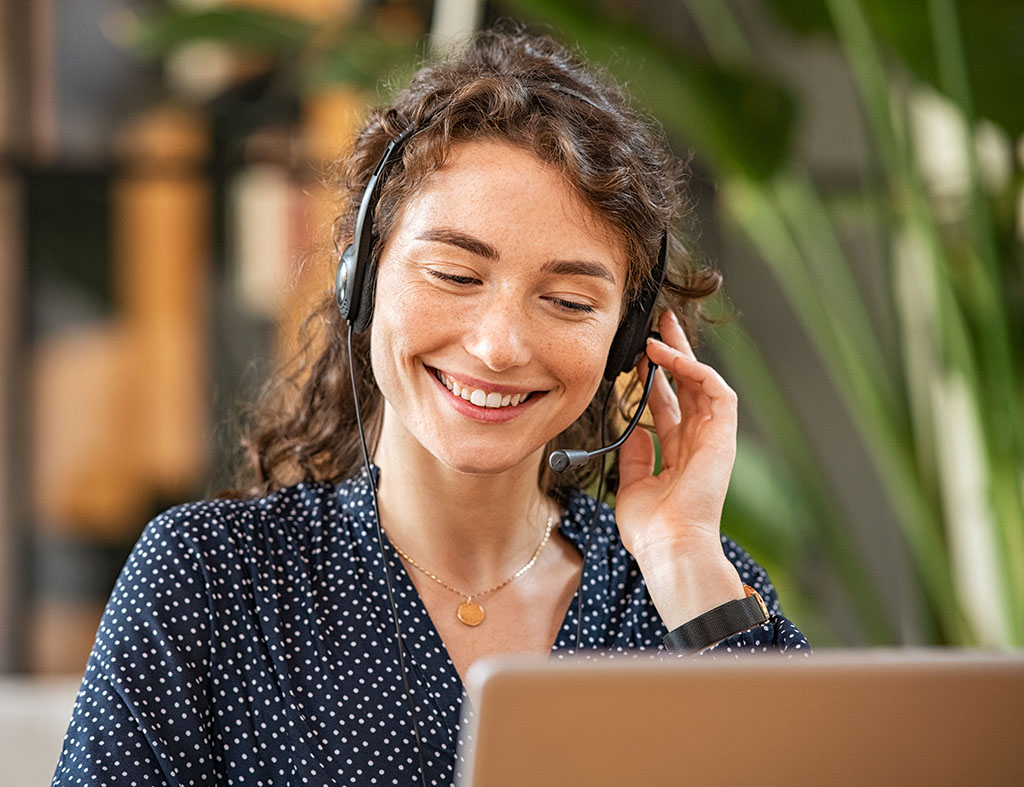Smiling woman talking to customer on headphones